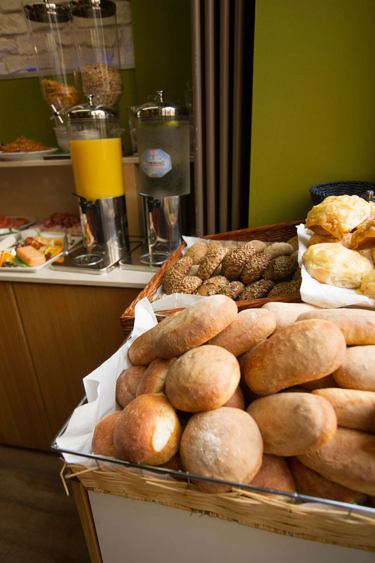 Brotkorb mit Brötchen sowie Saft- und Wasserspender im Hintergrund
